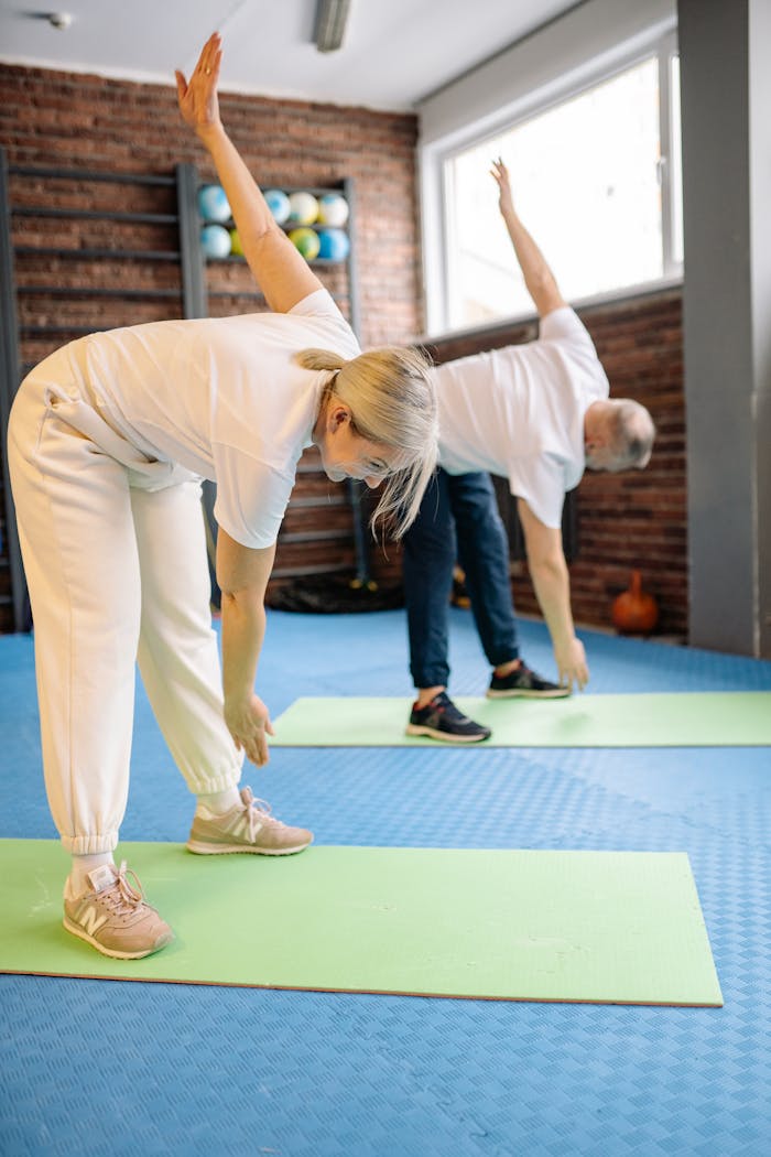 services-03 Senior adults stretch on mats in a fitness gym, promoting a healthy lifestyle.