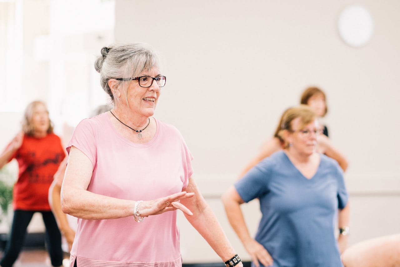 hero-img Senior women participating in a lively and joyful group exercise session indoors.