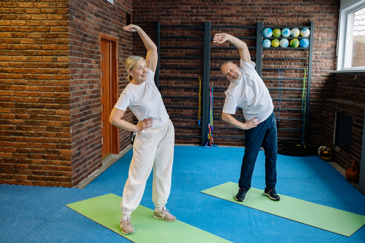 services-01 Elderly couple stretching on yoga mats in a home gym, embracing a healthy lifestyle.